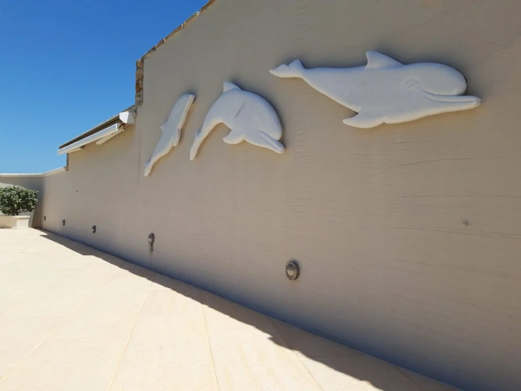 Three marble dolphins in relief on the outdoor wall of Kouros Art Hotel, Naxos, 2016